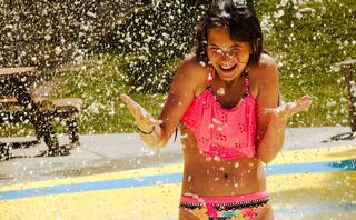 Girl splashing in water at splash and spray pad