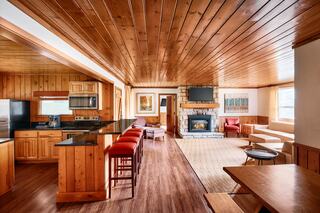 A spacious, wooden interior features a cozy living area with a fireplace, kitchen, and comfortable seating, creating a warm ambiance.