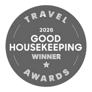 A gray circular badge featuring "2026 Good Housekeeping Winner" and "Travel Awards," highlighting a recognition or achievement in travel.