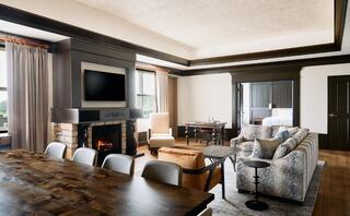 A stylish, open living area featuring a cozy fireplace, modern furniture, a large dining table, and a warm, inviting atmosphere.