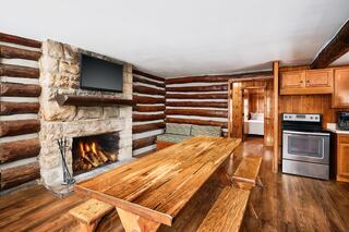 A cozy wooden room features two double beds, a mirror, and a window, creating a warm, inviting atmosphere.