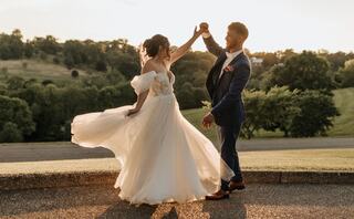 A couple embraces lovingly in a garden, surrounded by lush greenery and vibrant flowers, capturing a tender wedding moment.