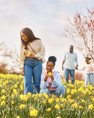 A joyful woman gives a playful piggyback ride to a smiling girl, both radiating happiness against a lush, sunny background.