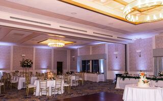 A couple shares a romantic dance at their wedding reception, surrounded by guests enjoying the celebration in an elegant venue.
