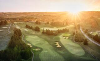 A grand, white mansion surrounded by lush greenery and rolling hills, with a winding path leading to its entrance.