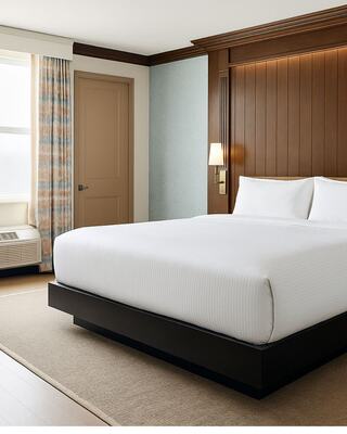 A modern hotel room featuring a large, neatly made bed, wood panel accents, stylish curtains, and a cozy atmosphere.