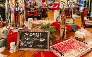 A festive table with hot chocolate and candy canes, decorated with holiday cheer and a cozy atmosphere, inviting guests to enjoy seasonal treats.