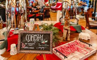 A festive table displays hot chocolate and candy canes, with a decorative sign announcing the seasonal treat available in the evening.