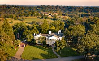 A picturesque mansion set amidst lush greenery, rolling hills, and a serene landscape, capturing the essence of elegance and tranquility.