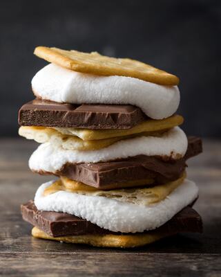 A tall stack of s'mores features layers of toasted marshmallows, chocolate, and graham crackers, tempting with their gooey goodness.