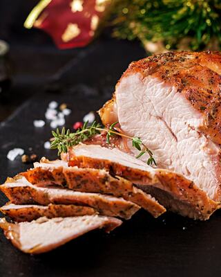 Juicy, sliced roasted pork adorned with herbs, surrounded by festive decorations and salt, presenting a mouthwatering holiday feast.
