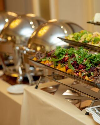 A lavish buffet setup featuring silver chafing dishes filled with colorful salads and dishes, creating an inviting dining atmosphere.