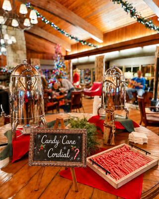 A cozy holiday scene features hot cocoa dispensers, candy canes, and a festive tree, enhancing a warm, inviting atmosphere.
