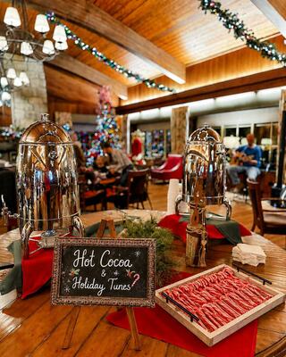 A cozy holiday scene features hot cocoa dispensers, candy canes, and a festive tree, enhancing a warm, inviting atmosphere.