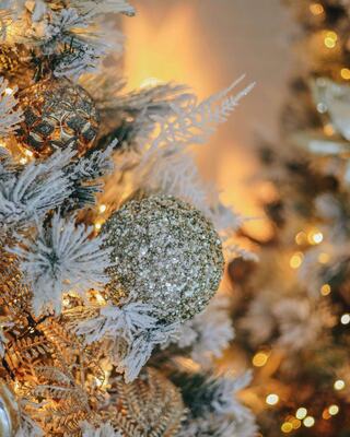 A beautifully decorated Christmas tree features glittering ornaments and frosted branches, creating a warm, festive atmosphere.