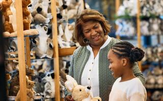 A grandmother and granddaughter joyfully explore a store filled with stuffed animals, sharing smiles and special moments together.