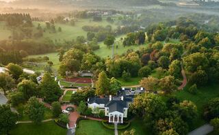 A serene landscape features rolling hills, a peaceful pond, and lush greenery, illuminated by soft morning light and gentle mist.