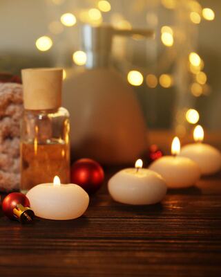 A serene setting with lit candles, decorative ornaments, and a bottle of oil, creating a calming and festive ambiance.
