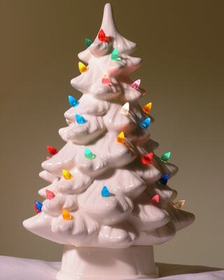 A ceramic Christmas tree adorned with colorful, light-shaped ornaments, evoking a nostalgic holiday spirit.