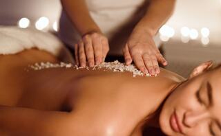 A tranquil spa scene with a person receiving a salt scrub on their back, promoting relaxation and self-care in a soothing ambiance.