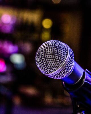 A close-up of a microphone with a blurred, colorful background suggesting a lively atmosphere, perfect for performances or speeches.