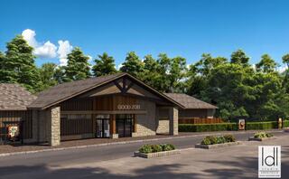 A modern zoo entrance features a stone and wood design, surrounded by greenery and trees under a clear blue sky.