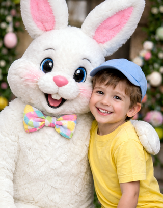 A joyful child in a yellow shirt and cap smiles alongside a large, friendly bunny with a colorful bow tie, surrounded by vibrant Easter decorations.