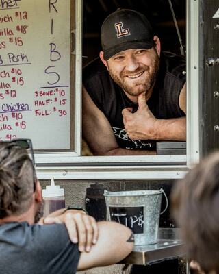 man smiling inside food truck window at customer