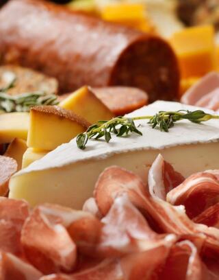 A delicious spread featuring assorted cheeses, cured meats, and garnishes, creating a tempting and visually appealing charcuterie board.