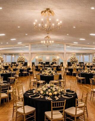 A beautifully decorated banquet hall featuring elegant tables, lavish floral arrangements, and a stunning chandelier, perfect for celebrations.