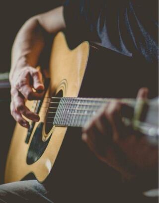 A close-up of hands strumming an acoustic guitar, showcasing a blend of passion and skill in a soft, atmospheric setting.