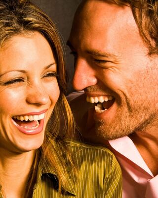 Two people share a joyful moment, laughing together with bright smiles and joyful expressions in a warm, friendly atmosphere.