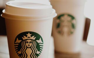 Two Starbucks coffee cups are prominently displayed, featuring the iconic green logo against a warm, softly lit background.