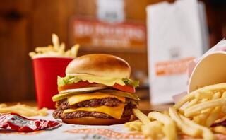 A juicy cheeseburger topped with lettuce, tomato, and pickles, paired with crispy fries and sauce at Route 88 Burgers & Brew