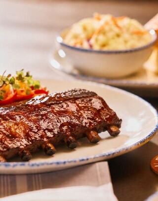 Juicy glazed ribs served on a plate with a side of colorful salad and coleslaw, ready to enjoy a delicious meal.