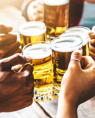 Cheers with several hands holding mugs of golden beer, capturing a joyful moment of celebration and camaraderie.
