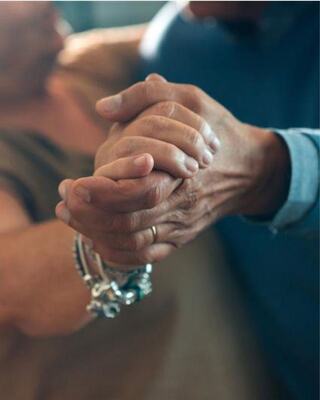 Two hands clasped together, showcasing connection and support, with one adorned in a silver bracelet, conveying warmth and intimacy.