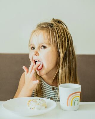 little girl licking her fingers at breakfast