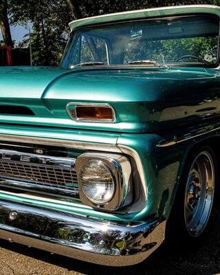 A classic teal Chevy truck with chrome details, capturing retro charm and nostalgia, parked under greenery, showcasing its vintage appeal.