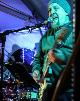 A musician passionately performs on stage, playing guitar and singing into a microphone, with colorful lights illuminating the scene.