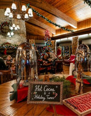 A cozy holiday setting features a festive tree, cheerful decorations, and a table with hot cocoa and treats, inviting warmth and celebration.