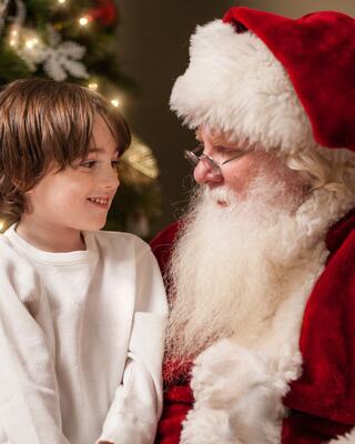 A mother holds her child close, both wrapped in a cozy blanket, surrounded by festive lights, radiating warmth and joy.