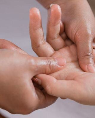 Two hands engage in a gentle palm massage, illustrating a nurturing or therapeutic touch between individuals.