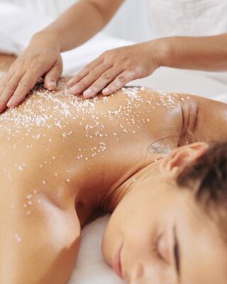 A person receives a spa treatment with a salt scrub applied to their back, promoting relaxation and rejuvenation.