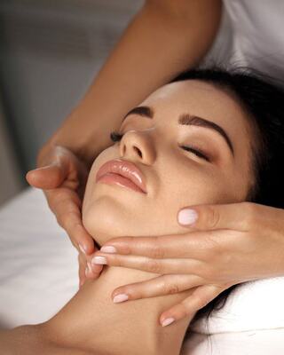 A serene woman relaxes as a skilled hand performs a facial massage, enhancing her natural beauty and promoting a sense of tranquility.