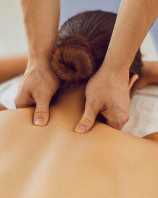 A person receiving a massage, focusing on the upper back, with hands applying pressure for relaxation and relief.